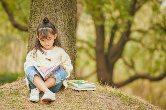 小女孩坐在树下读书